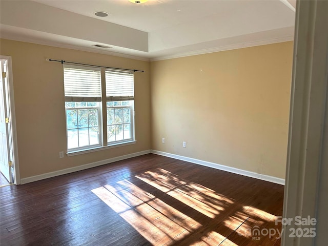 spare room with a raised ceiling, ornamental molding, and dark hardwood / wood-style flooring