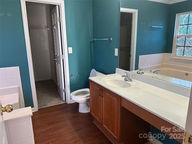 bathroom featuring vanity, a tub, hardwood / wood-style floors, and toilet