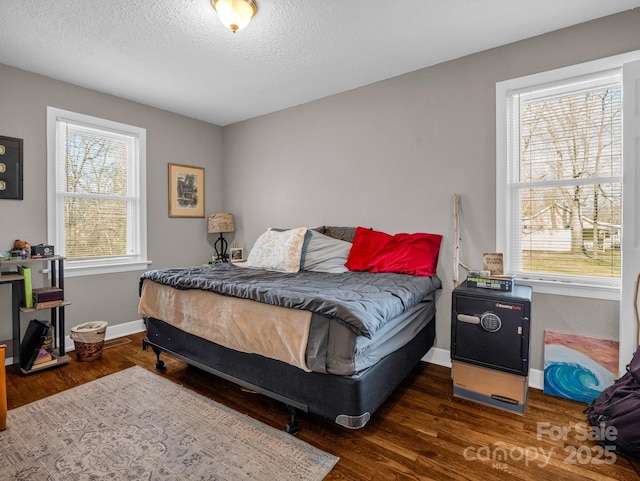 bedroom with multiple windows, dark wood-type flooring, and a textured ceiling