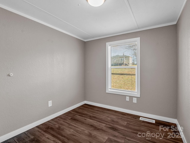 spare room with crown molding and dark wood-type flooring