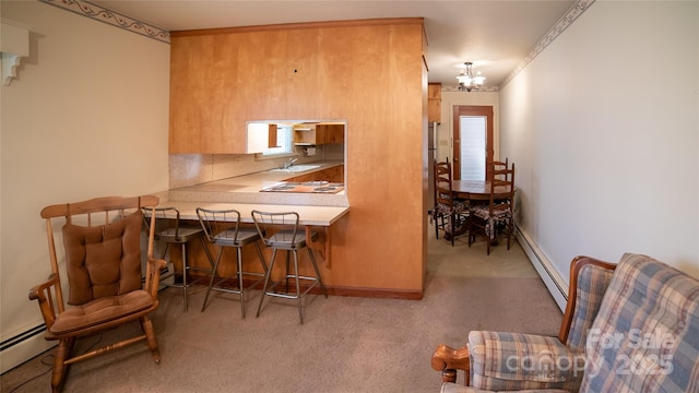 kitchen with a notable chandelier, baseboard heating, and light carpet