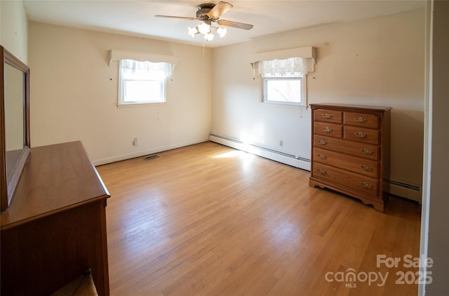 unfurnished bedroom with light wood-style flooring, multiple windows, and baseboard heating