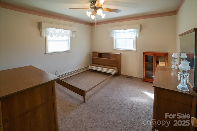 unfurnished bedroom with a baseboard heating unit, multiple windows, carpet, and visible vents