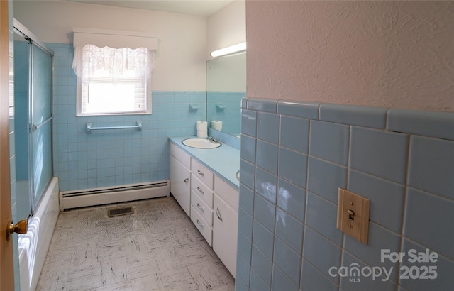 full bathroom featuring vanity, enclosed tub / shower combo, wainscoting, tile walls, and baseboard heating