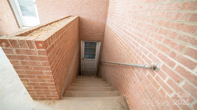 stairway featuring brick wall