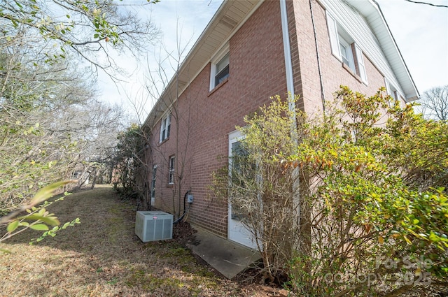 view of home's exterior with central AC unit and brick siding