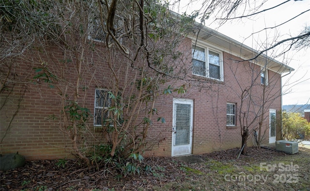 view of home's exterior featuring brick siding and central AC