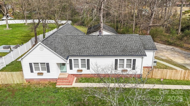 view of front of house featuring entry steps, a front lawn, fence private yard, and roof with shingles