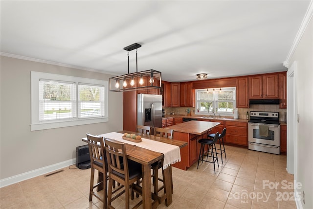 kitchen featuring under cabinet range hood, stainless steel appliances, backsplash, and visible vents