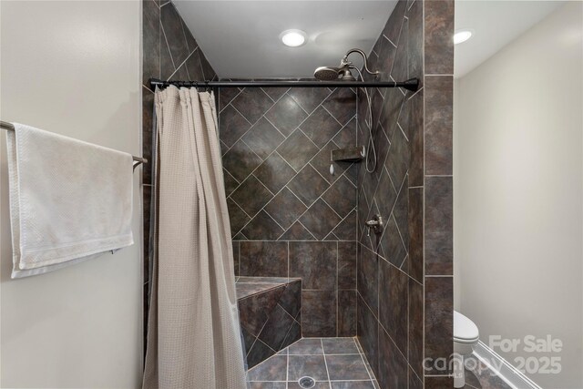 bathroom featuring toilet and a tile shower