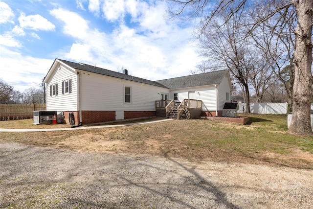 rear view of property featuring cooling unit, fence, brick siding, and a wooden deck