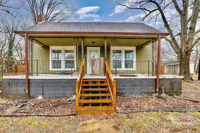 bungalow-style home with covered porch, roof with shingles, and a chimney