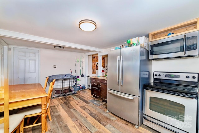 kitchen with light wood-type flooring, appliances with stainless steel finishes, light countertops, and dark brown cabinets