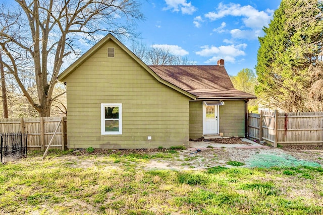back of property with a shingled roof, fence, and a chimney
