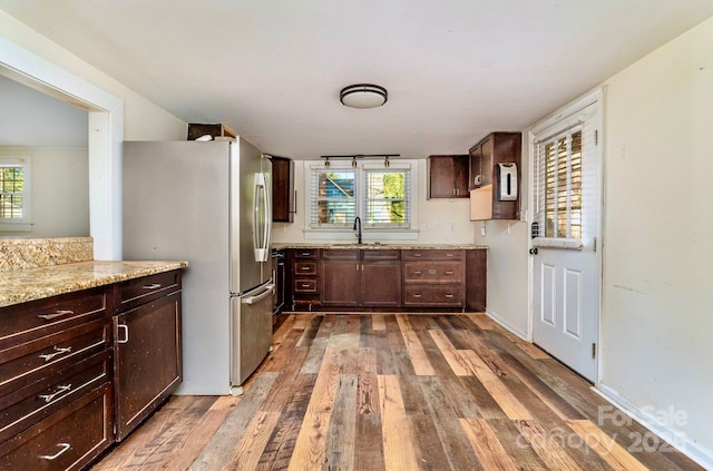 kitchen with wood-type flooring, a wealth of natural light, a sink, and freestanding refrigerator