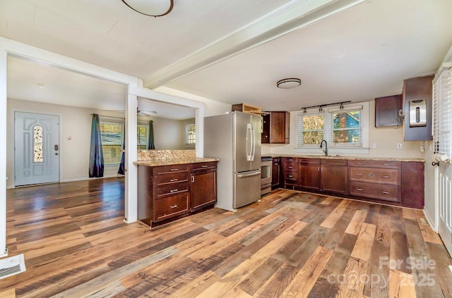 kitchen featuring visible vents, wood finished floors, beam ceiling, appliances with stainless steel finishes, and a sink