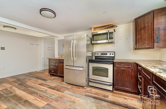 kitchen featuring light wood-style flooring, light stone countertops, dark brown cabinetry, and appliances with stainless steel finishes