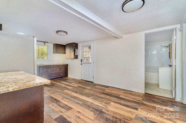 kitchen featuring freestanding refrigerator, dark brown cabinetry, dark wood-style floors, and baseboards