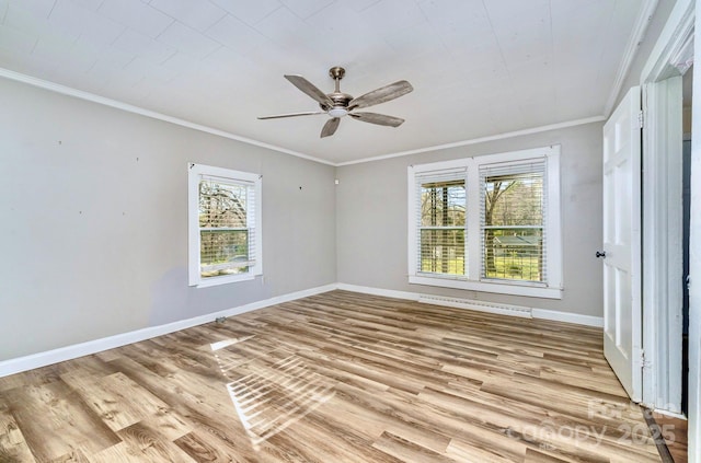empty room featuring ornamental molding, a healthy amount of sunlight, a ceiling fan, and light wood finished floors