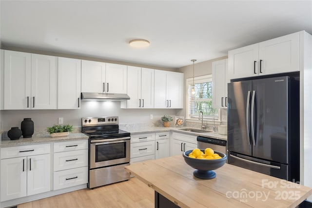 kitchen with white cabinets, stainless steel appliances, light wood-type flooring, under cabinet range hood, and a sink