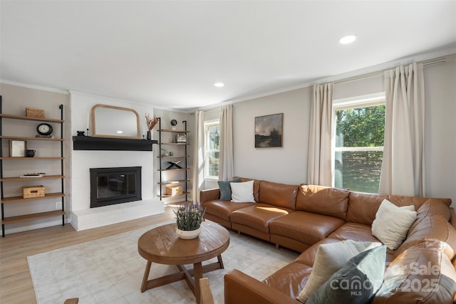 living area featuring a large fireplace, ornamental molding, recessed lighting, and light wood-style floors