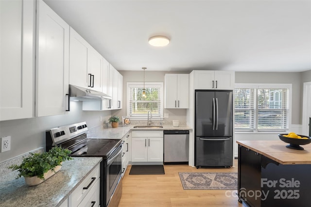 kitchen featuring under cabinet range hood, stainless steel appliances, a sink, wood counters, and white cabinets