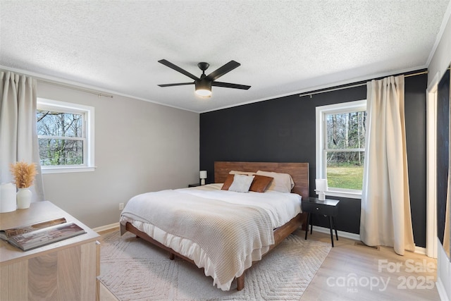 bedroom featuring multiple windows, a textured ceiling, and light wood finished floors