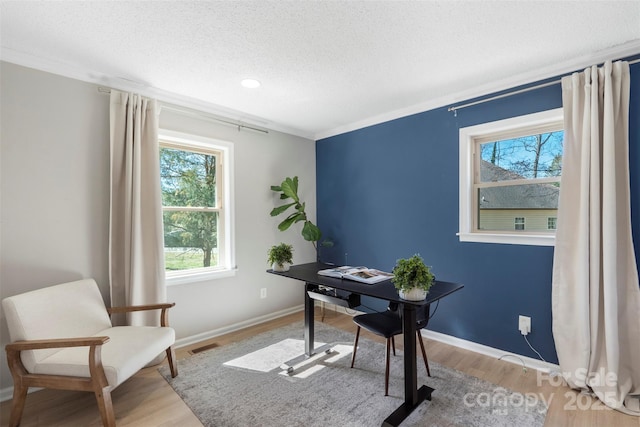 home office with a textured ceiling, wood finished floors, visible vents, and baseboards