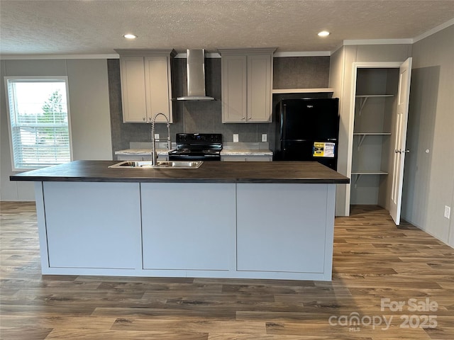 kitchen with sink, dark wood-type flooring, gray cabinets, black appliances, and wall chimney exhaust hood