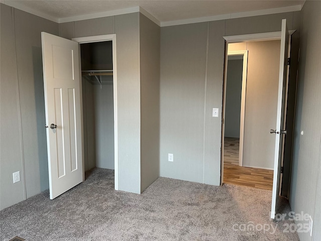 unfurnished bedroom with ornamental molding, carpet floors, and a closet