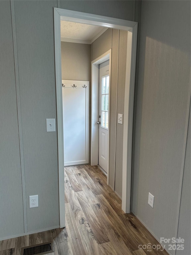 hall with hardwood / wood-style flooring and crown molding