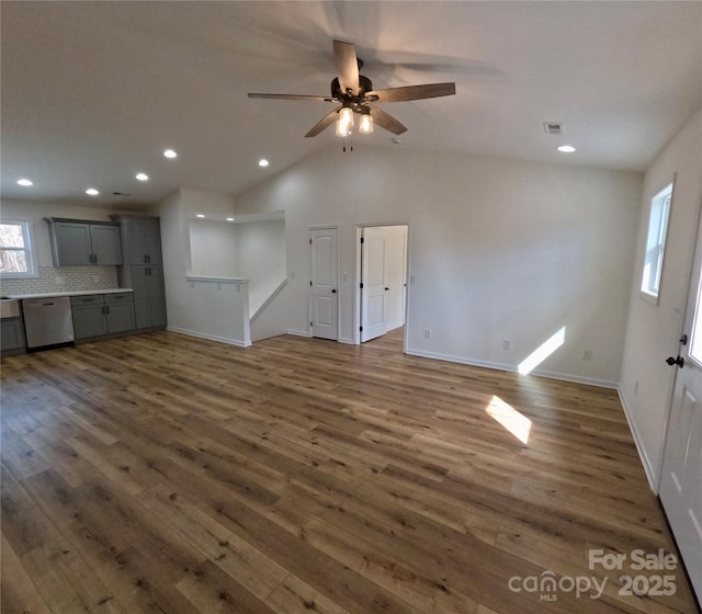 unfurnished living room featuring lofted ceiling, dark wood-type flooring, and ceiling fan