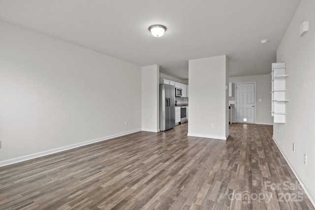 unfurnished living room with dark wood-style flooring and baseboards