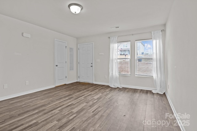 spare room featuring baseboards and wood finished floors