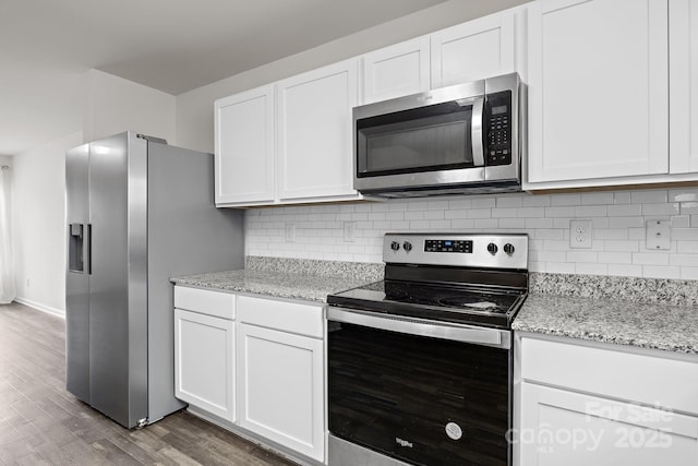 kitchen featuring stainless steel appliances, wood finished floors, white cabinetry, light stone countertops, and tasteful backsplash