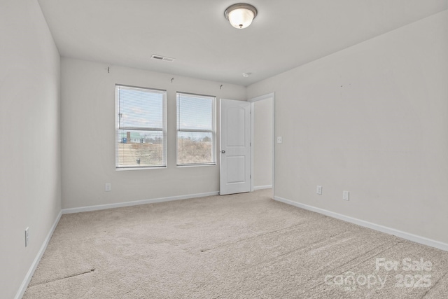 spare room featuring carpet, visible vents, and baseboards