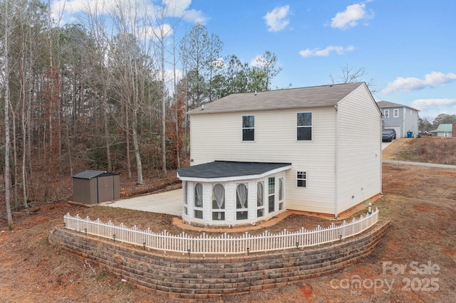 rear view of property featuring an outbuilding, fence, and a storage shed