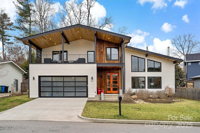 contemporary home featuring entry steps, an attached garage, a balcony, concrete driveway, and a front lawn