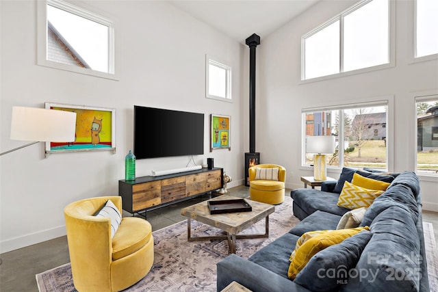 living area with a high ceiling, a wood stove, and baseboards