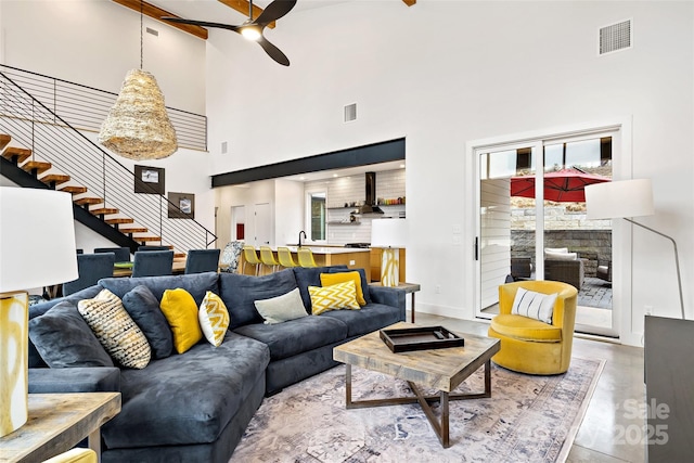 living area with ceiling fan, stairs, visible vents, and baseboards