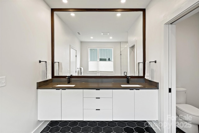 full bathroom with double vanity, a sink, toilet, and a shower stall