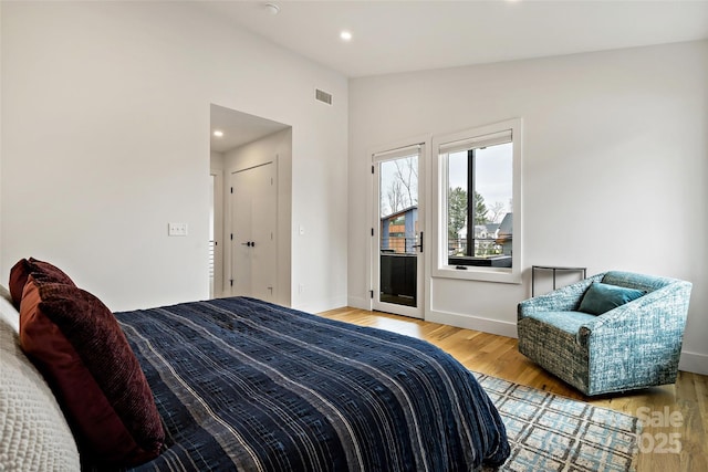 bedroom featuring visible vents, light wood-style flooring, vaulted ceiling, access to outside, and baseboards