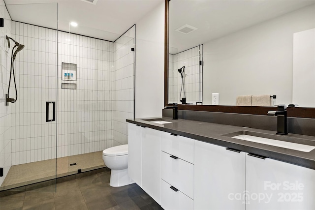 bathroom featuring toilet, double vanity, a sink, and visible vents