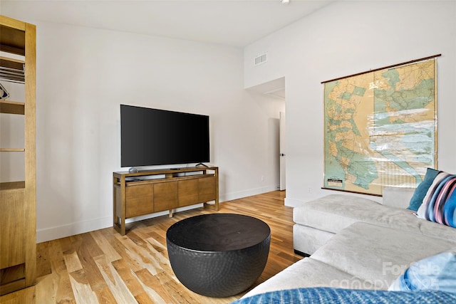 living room with baseboards, visible vents, and wood finished floors