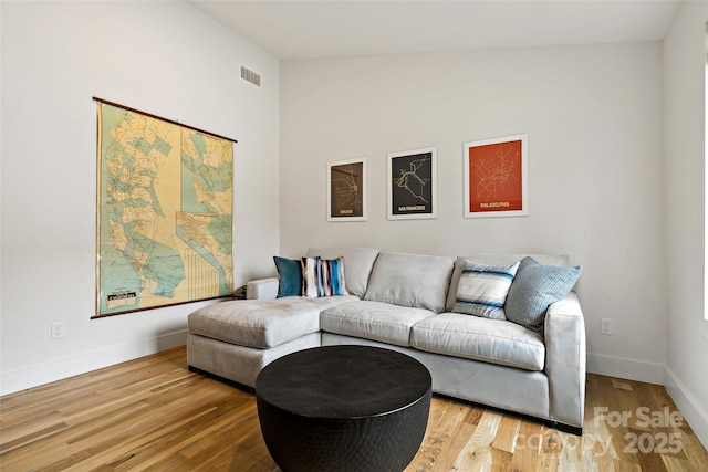 living area with vaulted ceiling, light wood-type flooring, visible vents, and baseboards