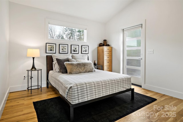 bedroom with lofted ceiling, light wood-style flooring, and baseboards