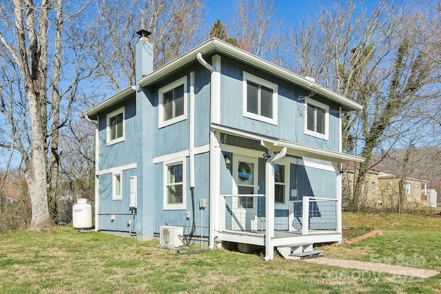 rear view of property featuring covered porch, a chimney, a yard, and ac unit