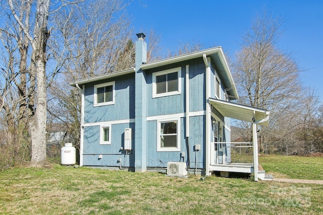 rear view of property featuring ac unit, a yard, and a chimney