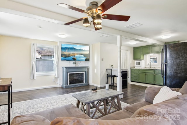 living area with dark wood-style floors, visible vents, a fireplace, and baseboards