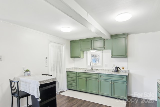 kitchen featuring green cabinetry, beam ceiling, dark wood-type flooring, and a sink